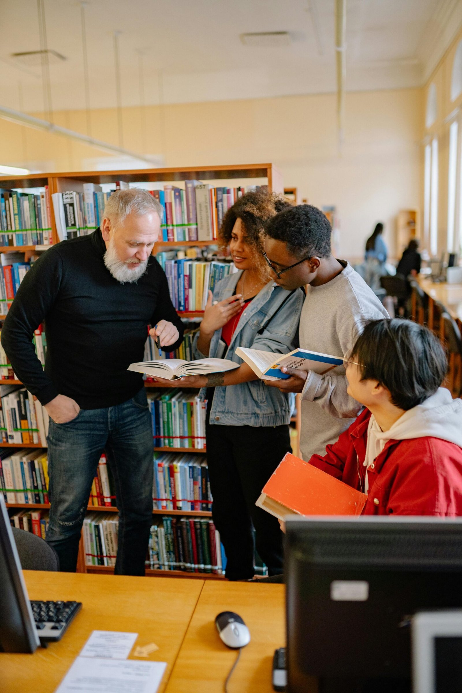 Four diverse students engaged in a collaborative study session in a library setting.