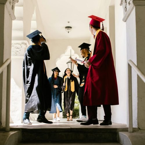 Group of diverse graduates celebrating together in a bright hallway.